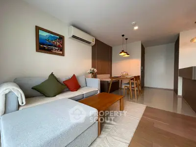 Modern living room with cozy seating and stylish dining area in open layout apartment.