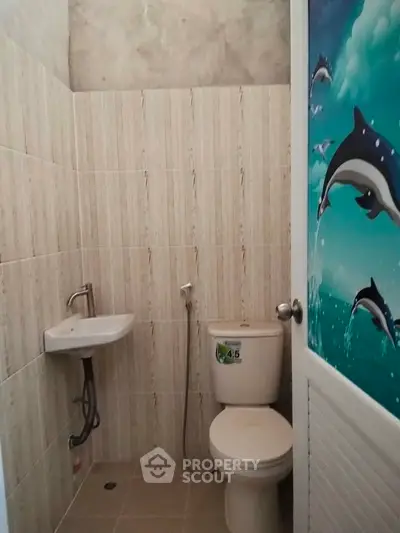 Compact bathroom with dolphin-themed door and basic fixtures