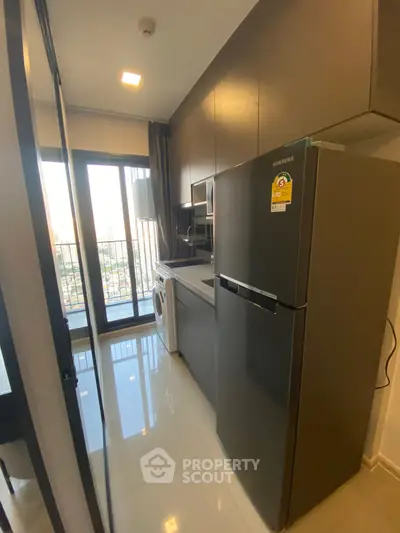 Modern kitchen with sleek appliances and balcony view in urban apartment.