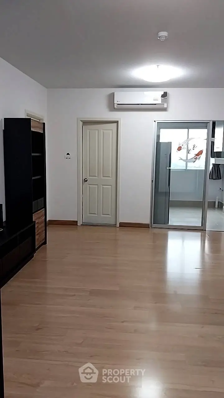 Spacious living room with wooden flooring and modern air conditioning unit.