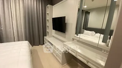 Modern bedroom with sleek TV unit and mirrored vanity in stylish apartment.