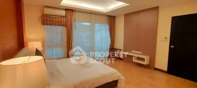Spacious bedroom with elegant lighting and large windows in modern apartment.