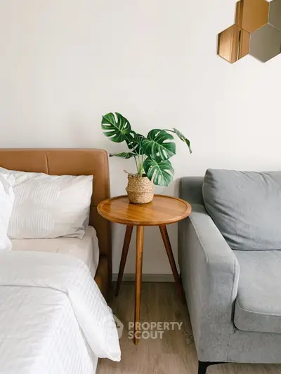 Stylish bedroom corner with cozy bed, modern sofa, and chic wooden side table with plant.