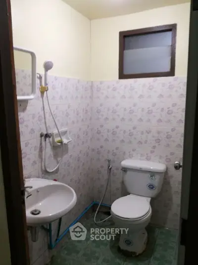 Cozy bathroom with floral tiles and essential fixtures