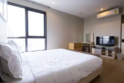 Modern bedroom with large window and sleek furnishings in urban apartment