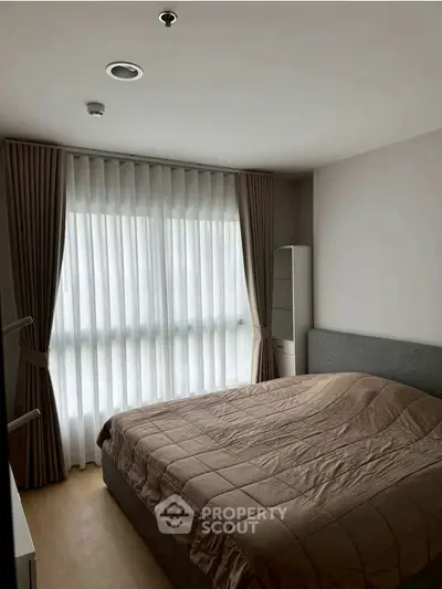 Cozy bedroom with large window and elegant curtains, perfect for relaxation and comfort.