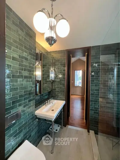 Luxurious bathroom with green tiled walls and elegant lighting fixtures.
