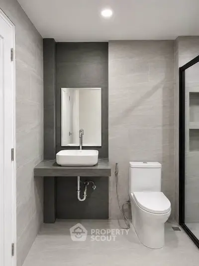 Modern bathroom with sleek design, featuring a wall-mounted sink and contemporary toilet.