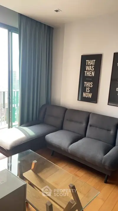 Modern living room with stylish sofa and glass coffee table, featuring floor-to-ceiling windows and chic wall art.