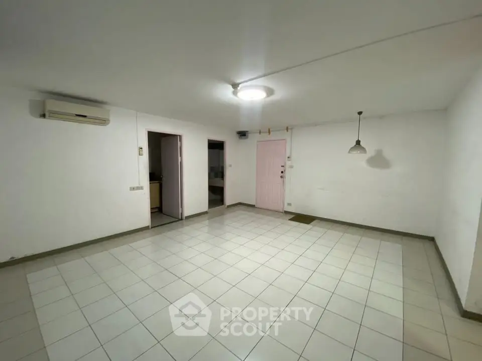 Spacious empty living room with tiled floor and air conditioning unit.