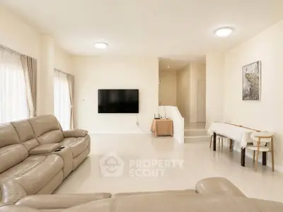 Spacious living room with modern beige leather sofas and wall-mounted TV, perfect for family gatherings.