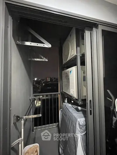 Compact balcony with air conditioning units and city view at night