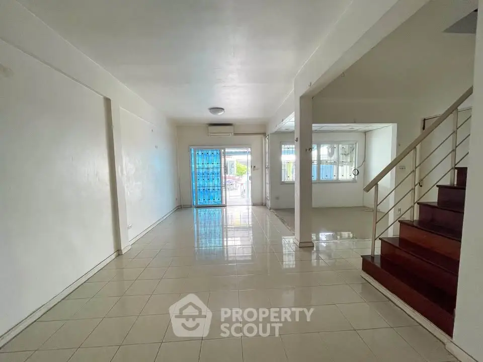 Spacious open-plan living area with tiled floors and staircase, perfect for modern living.