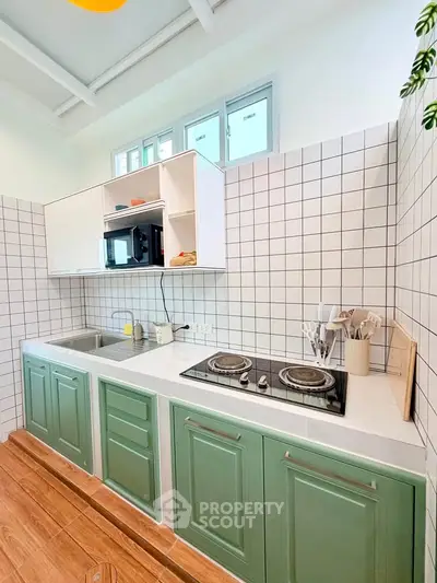 Charming kitchen with green cabinets and modern appliances, featuring a sleek electric stove and tiled backsplash.