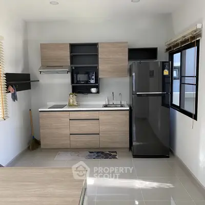 Modern kitchen with sleek cabinets, stainless steel fridge, and ample natural light.