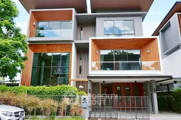 Modern three-story townhouse with large windows and lush greenery