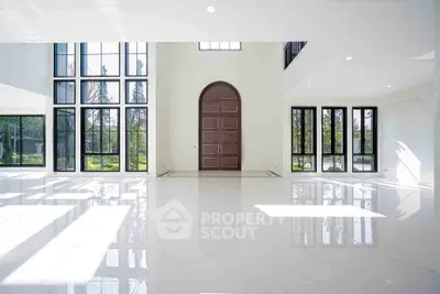 Spacious modern living room with large windows and high ceilings, offering abundant natural light.