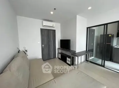 Modern living room with sleek furniture and glass partition leading to kitchen area.