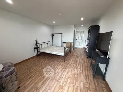 Spacious bedroom with wooden flooring and modern furnishings in a stylish apartment.