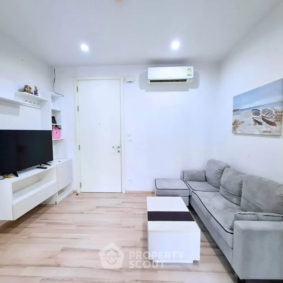 Modern living room with sleek furniture and wall-mounted TV in a cozy apartment.