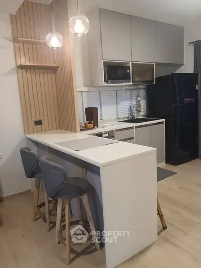 Modern kitchen with sleek design, featuring a breakfast bar and stylish lighting, perfect for contemporary living.