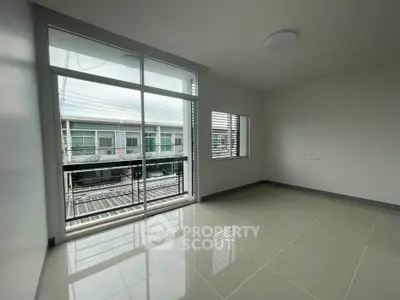 Spacious empty room with large windows and balcony access in modern apartment.