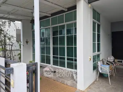 Charming modern home exterior with large windows and cozy patio area, perfect for relaxation and entertaining.