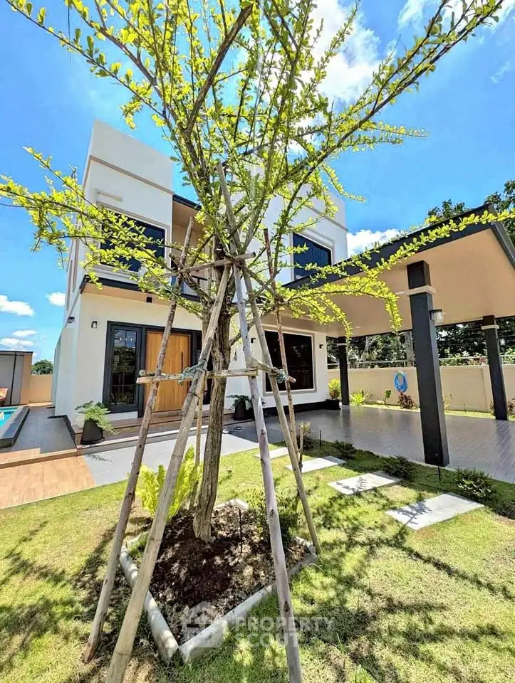 Modern two-story house with landscaped garden and spacious driveway under clear blue sky.