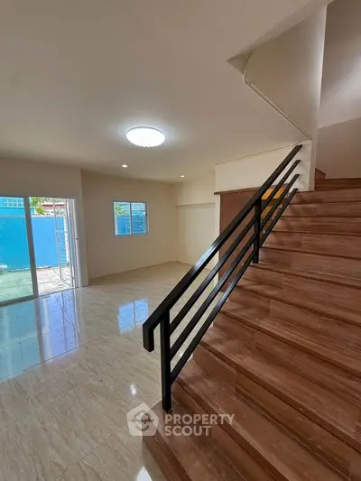 Spacious modern living room with elegant staircase and large windows for natural light.