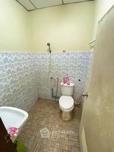 Compact bathroom with tiled walls and basic fixtures, ideal for budget-friendly living.