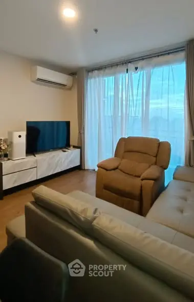 Cozy living room with modern furniture and large window offering natural light.