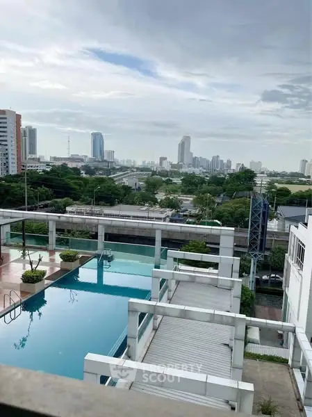 Stunning city view from a modern rooftop pool with lush greenery and skyline backdrop.