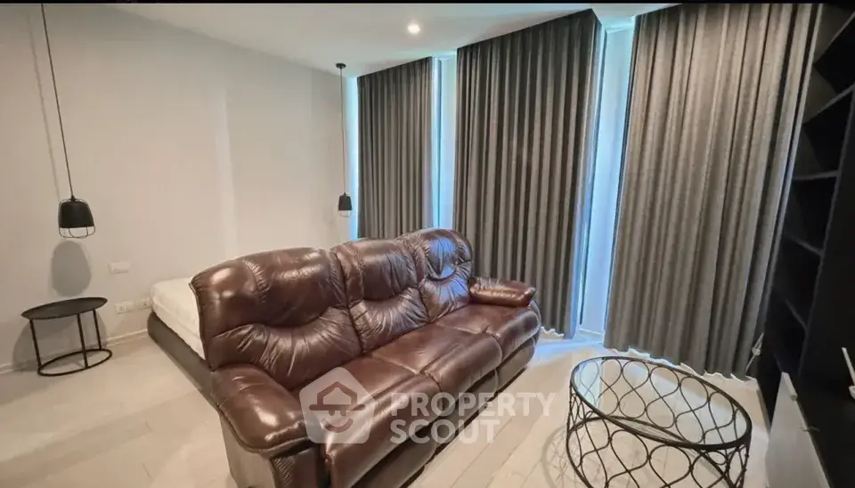 Modern living room with leather sofa and floor-to-ceiling curtains in a stylish apartment.