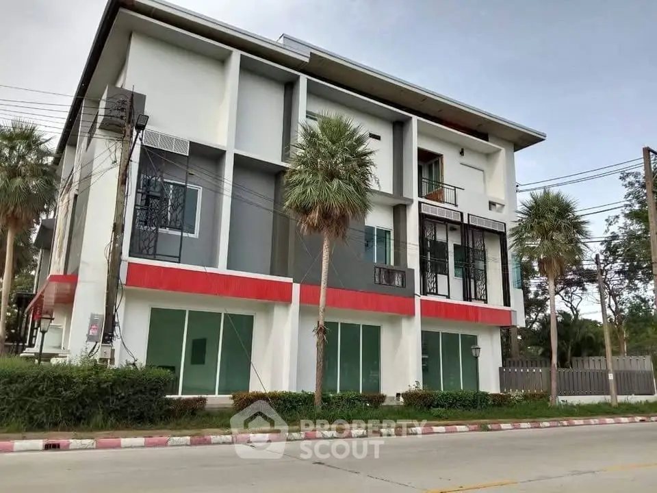 Modern three-story building with palm trees and street view, ideal for commercial or residential use.