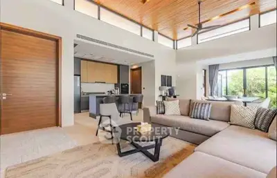 Spacious modern living room with open kitchen and large windows offering natural light.