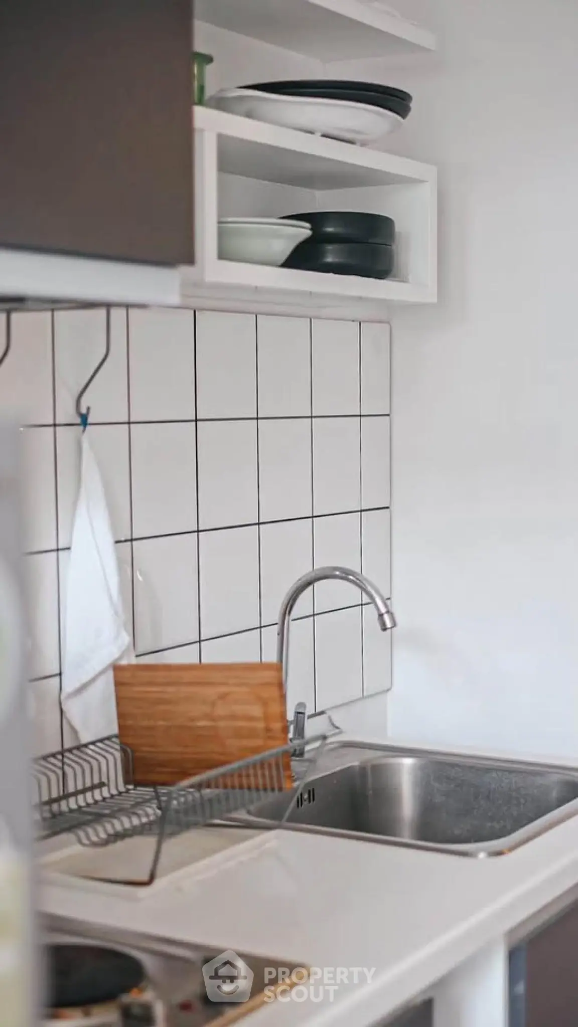 Modern kitchen with sleek sink and tiled backsplash, featuring open shelving and compact design.