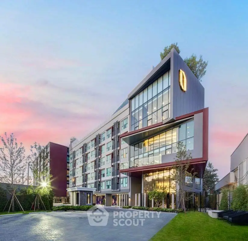 Modern apartment building with sleek design and large windows at sunset.