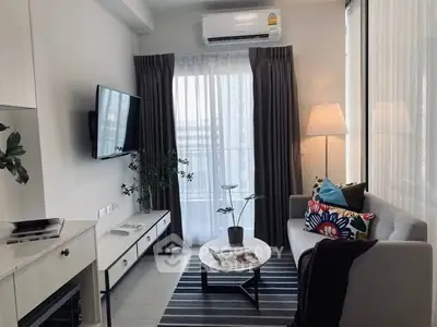 Modern living room with stylish decor, featuring a cozy sofa, wall-mounted TV, and large window with curtains.