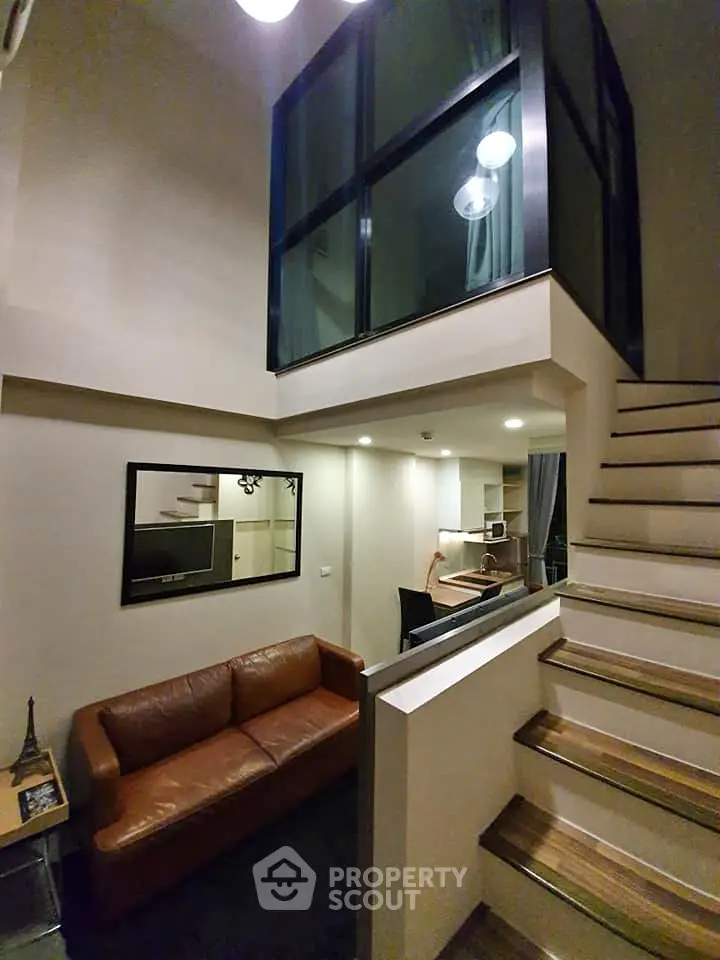 Modern loft-style living room with high ceilings and stylish staircase