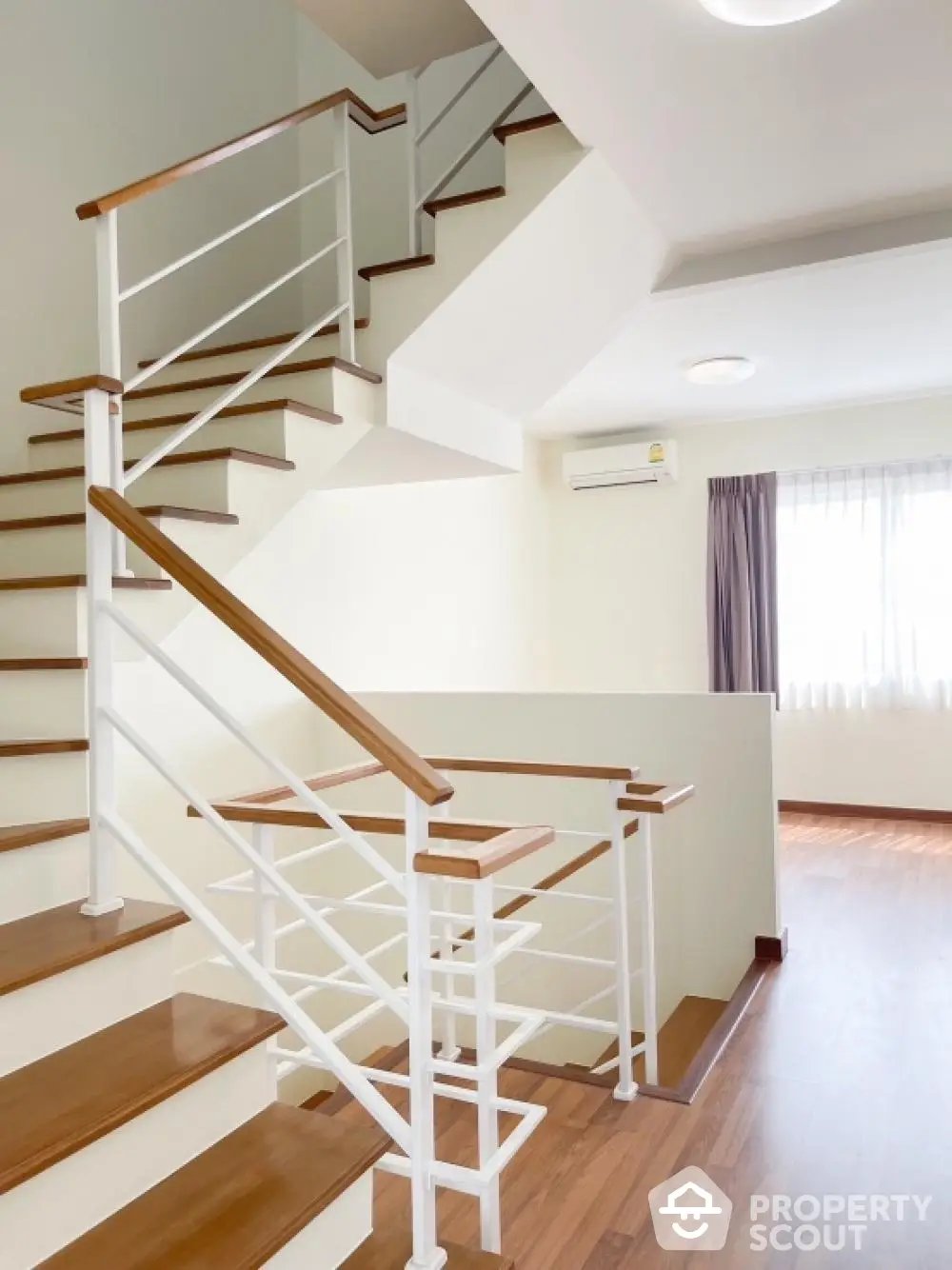 Bright and airy multi-level home interior with elegant wooden staircase, pristine white walls, and warm wooden flooring, perfect for modern living.