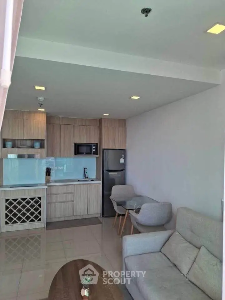Modern open-layout kitchen and living room with sleek furniture and appliances.
