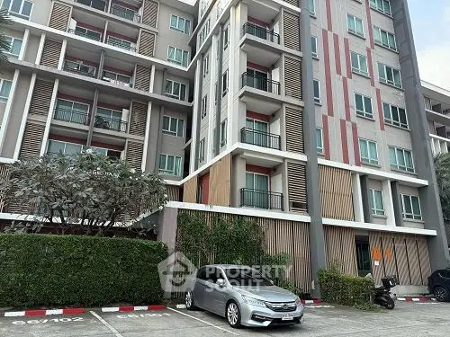 Modern apartment building exterior with parking area and lush greenery