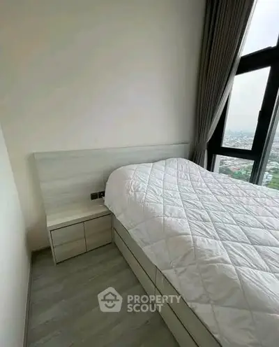 Modern bedroom with large window offering stunning city view, featuring sleek design and cozy ambiance.