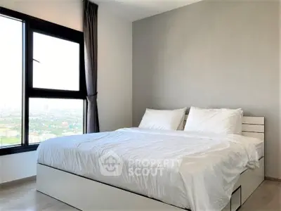 Bright bedroom with large window offering stunning city views, featuring a cozy double bed and modern decor.