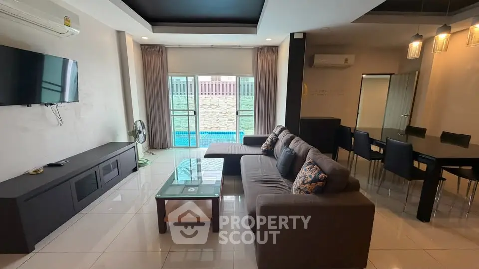 Spacious living room with modern decor and pool view, perfect for relaxation and entertainment.