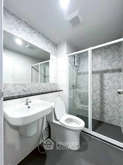 Modern bathroom with sleek design, featuring a glass shower enclosure and contemporary fixtures.