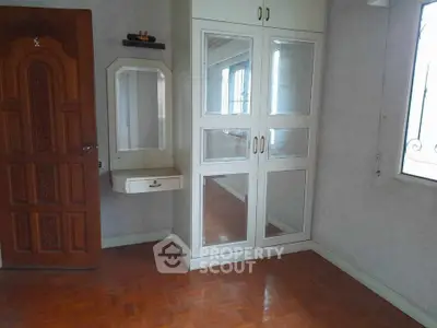 Spacious bedroom with wooden flooring and mirrored wardrobe
