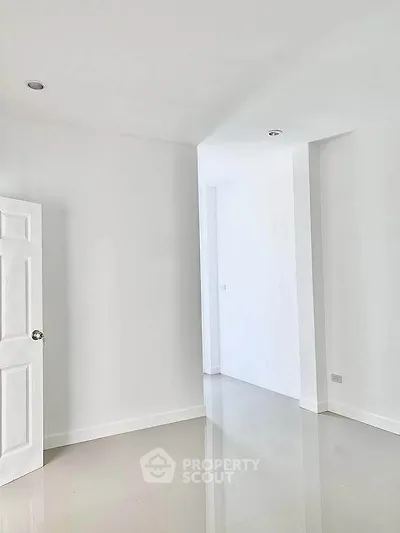 Spacious empty room with glossy tiled floors and white walls, perfect for customization.