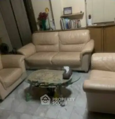 Cozy living room with beige leather sofas and glass coffee table.