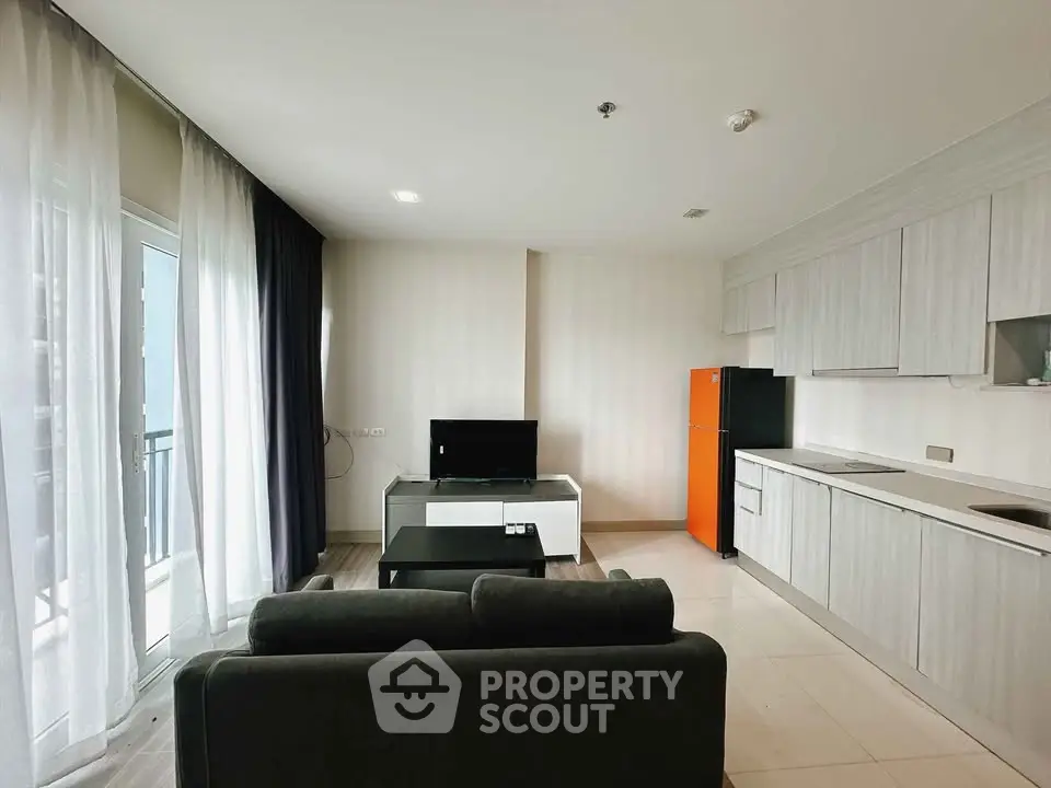 Modern living room with sleek kitchen and balcony access in a stylish apartment.